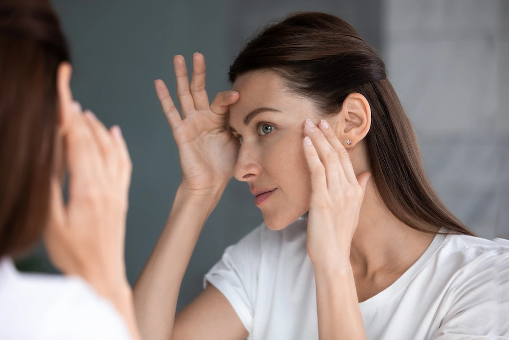 woman looking in the mirror touching her face